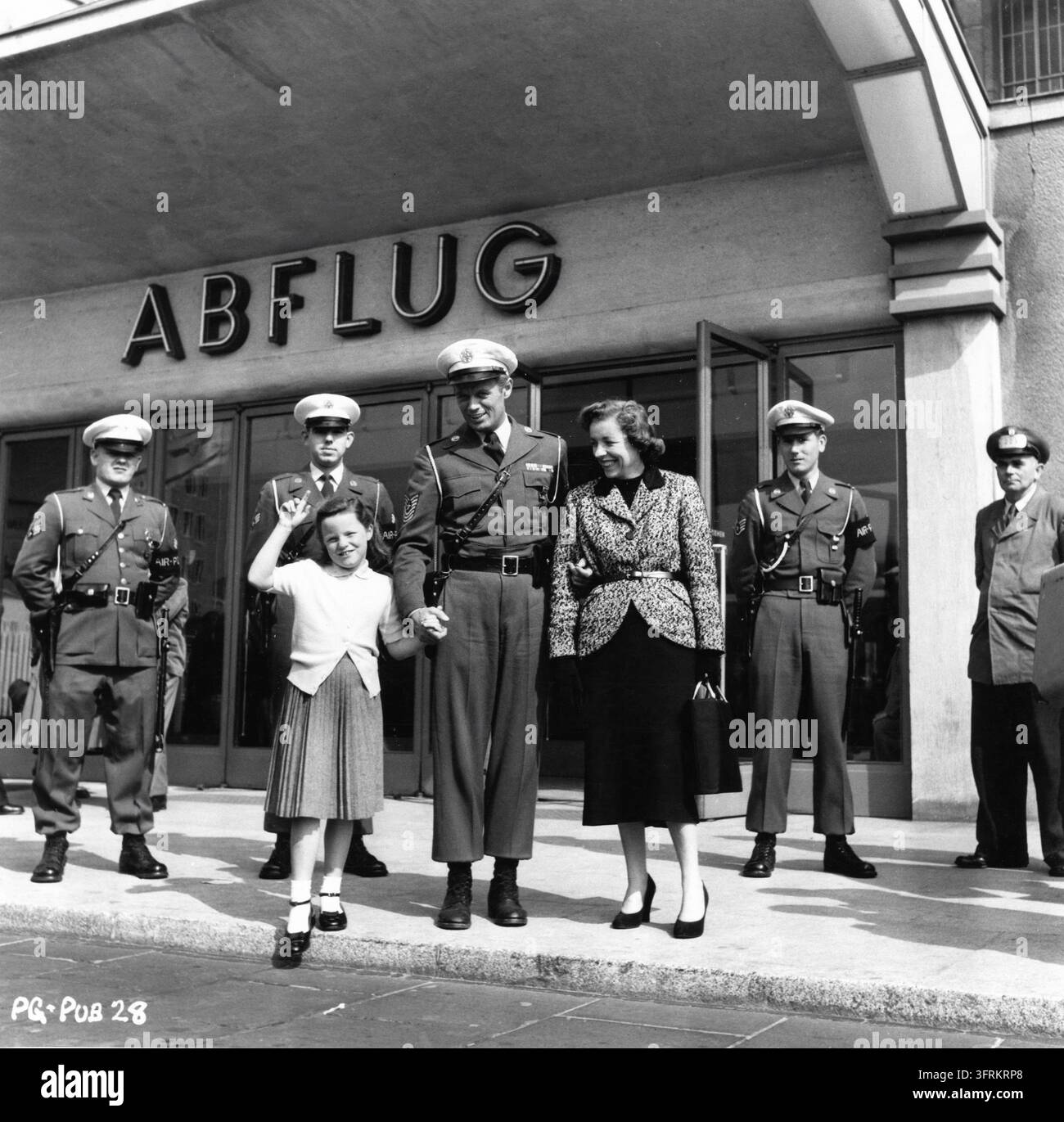 RICHARD WIDMARK im Kostüm als Air Police Sergeant Joe Lawrence am Setort ungeplant im Juli 1954 mit seiner Tochter ANN und seiner Frau JEAN am Tempelhof-Flughafen in Berlin während der Dreharbeiten zu A PRIZE OF GOLD 1955 Regisseur MARK ROBSON Roman Max Catto Drehbuch Robert Buckner und John Paxton Musik Malcolm Arnold Produzent Phil C. Samuel Ausführende Produzenten Irving Allen und Albert R. Broccoli Warwick Film Productions / Columbia Pictures Corporation Stockfoto
