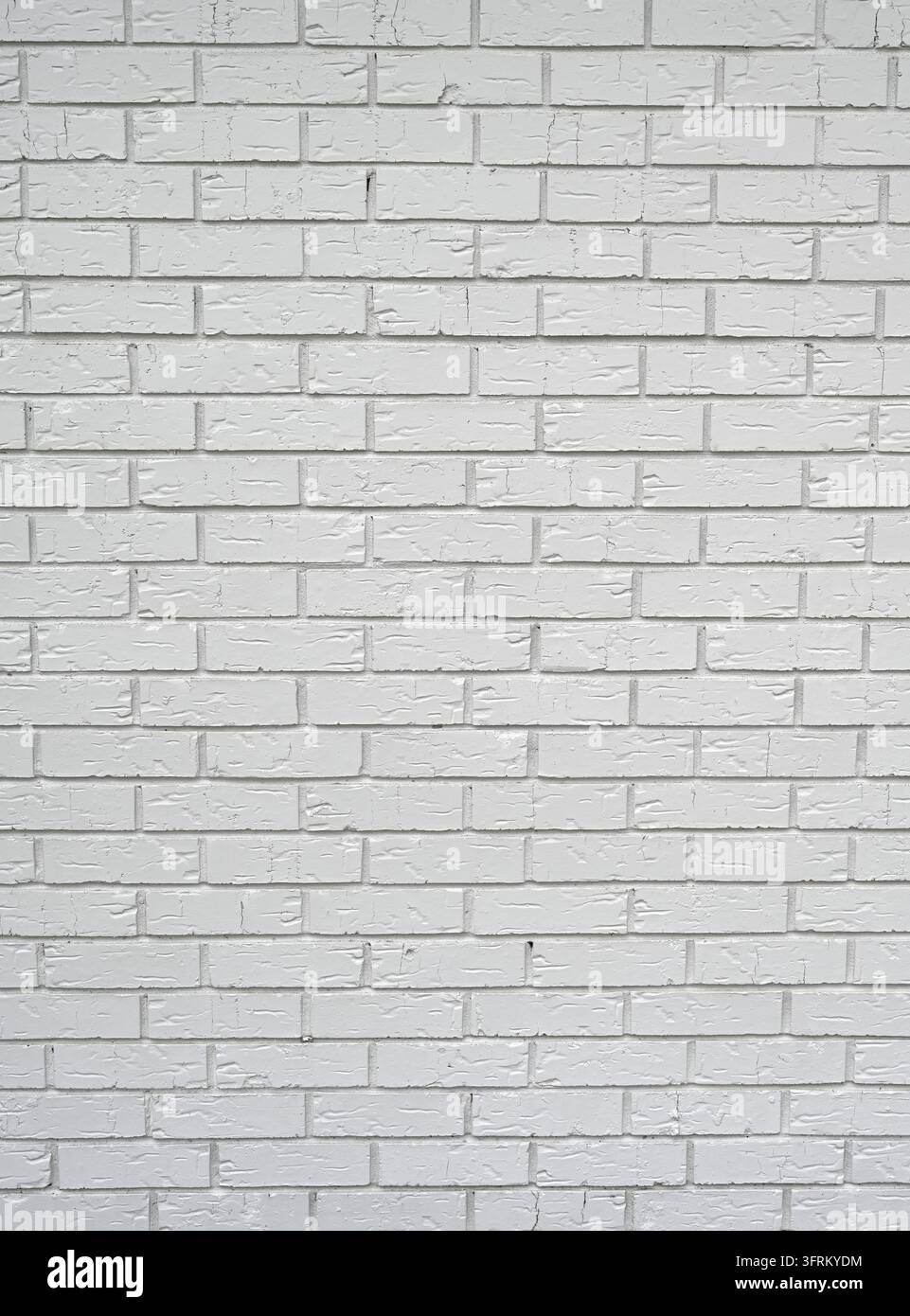 Weiß gestrichener Lehmziegel und Mörtelmauerwerk in einer vertikalen Komposition, das ein Standard-Stufenmuster zeigt, mit vertieften rauen Fugen Stockfoto
