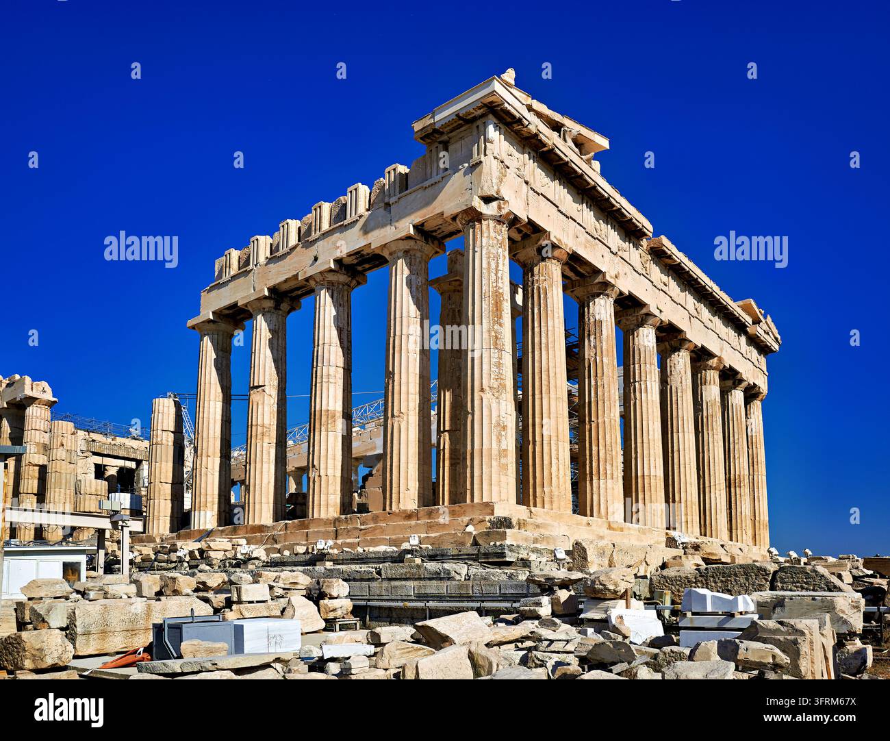 Dorische Säulen des Tempels der Athena aus dem 5. Jahrhundert v. Chr. unter einem klaren blauen Himmel, mit Restaurierungssgerüst und Marmorblöcken im Vordergrund Stockfoto