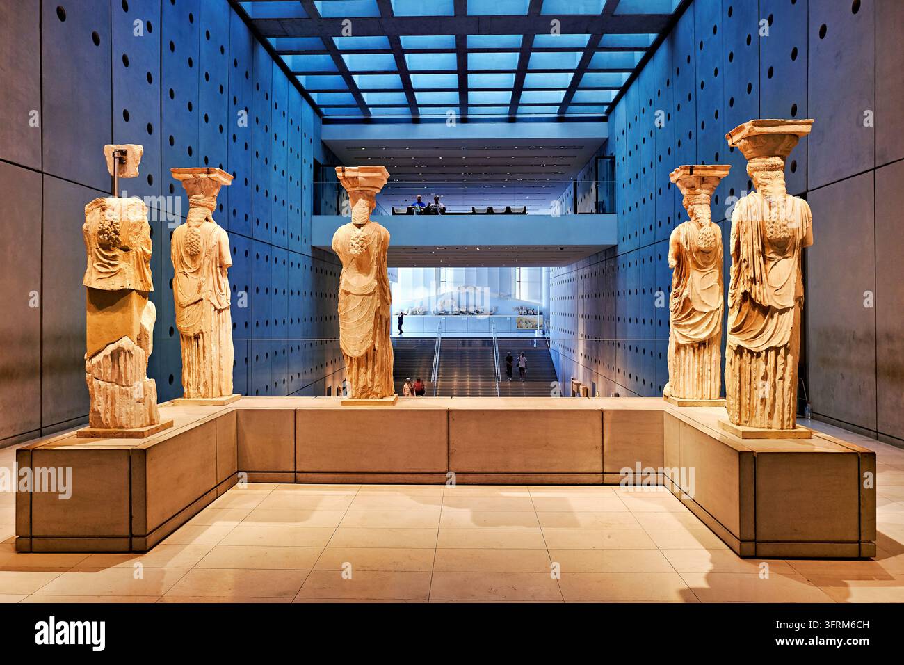 Rückansicht der Marmor-Karyatidenstatuen vom Erechtheion, die im Akropolis-Museum in Athen, Griechenland, ausgestellt sind, mit Besuchern in der Ferne. Stockfoto