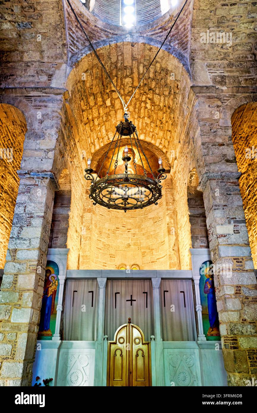 Eine Metall-Polyelos-Lampe hängt unter einer Kuppel in einer orthodoxen Kirche in Athen, Griechenland, mit Stein- und Ziegelmauern und einer Marmor-Iconostase. Stockfoto