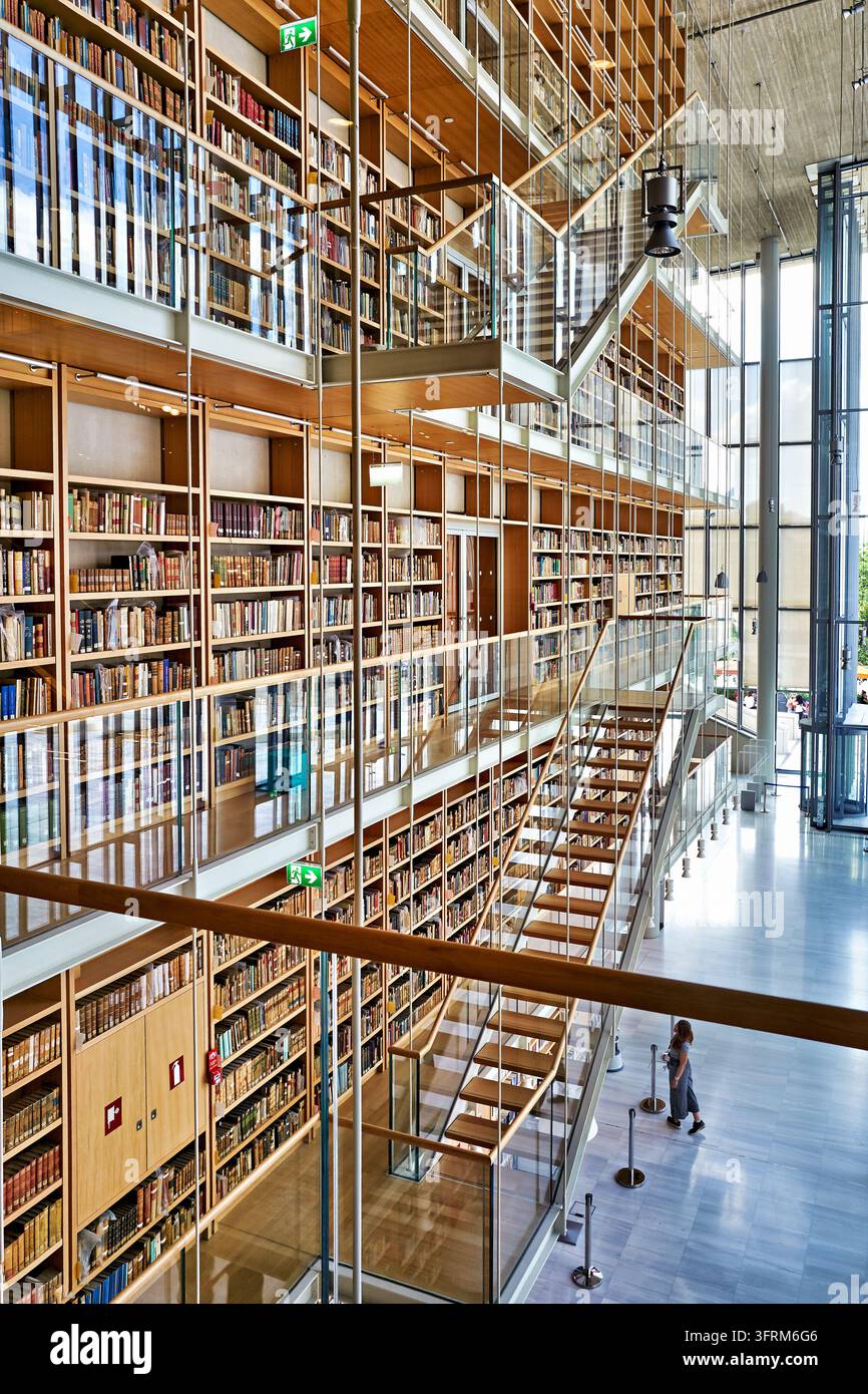 Ein Besucher steht unter GlasTreppen und mehrstufigen Bücherregalen im Kulturzentrum der Stavros Niarchos Stiftung in Athen, Griechenland. Stockfoto