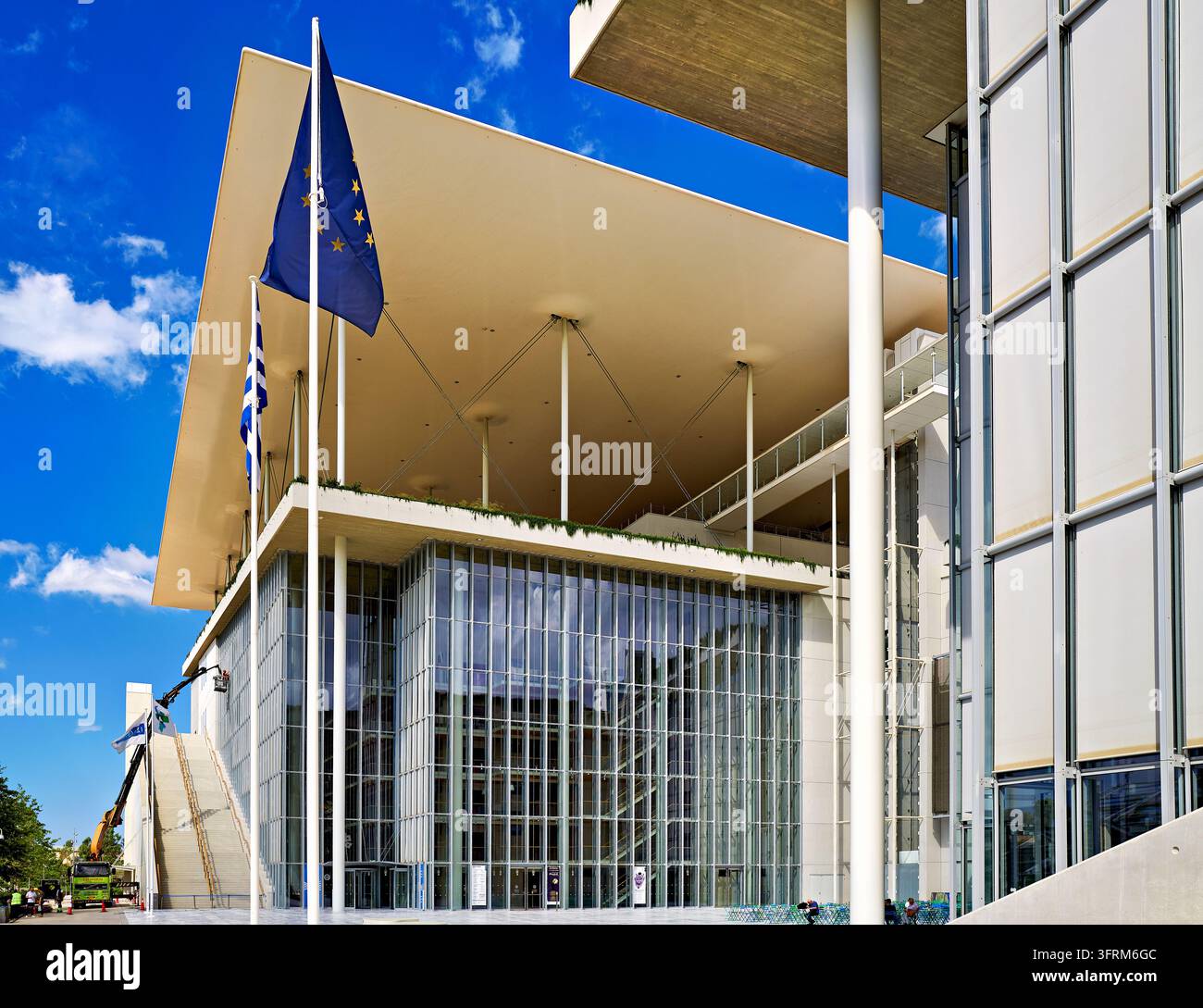 Dünn-Säulen-Kanopy über Glasfassaden des von Renzo Piano entworfenen SNFCC in Kallithea, Griechenland, mit EU- und griechischen Flaggen an einem Sommermorgen Stockfoto