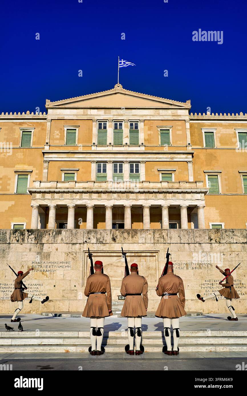 Präsidialgardisten in sommerlichen Khaki-Uniformen am Grabmal des Unbekannten Soldaten, Syntagma-Platz, Griechenland, unter der griechischen Flagge. Stockfoto