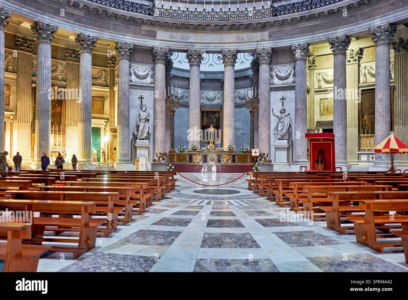 Holzbankreihen und Marmorboden führen zum Hochaltar unter der korinthischen Kolonnade der neoklassizistischen Kirche auf der Piazza del Plebiscito, Italien. Stockfoto