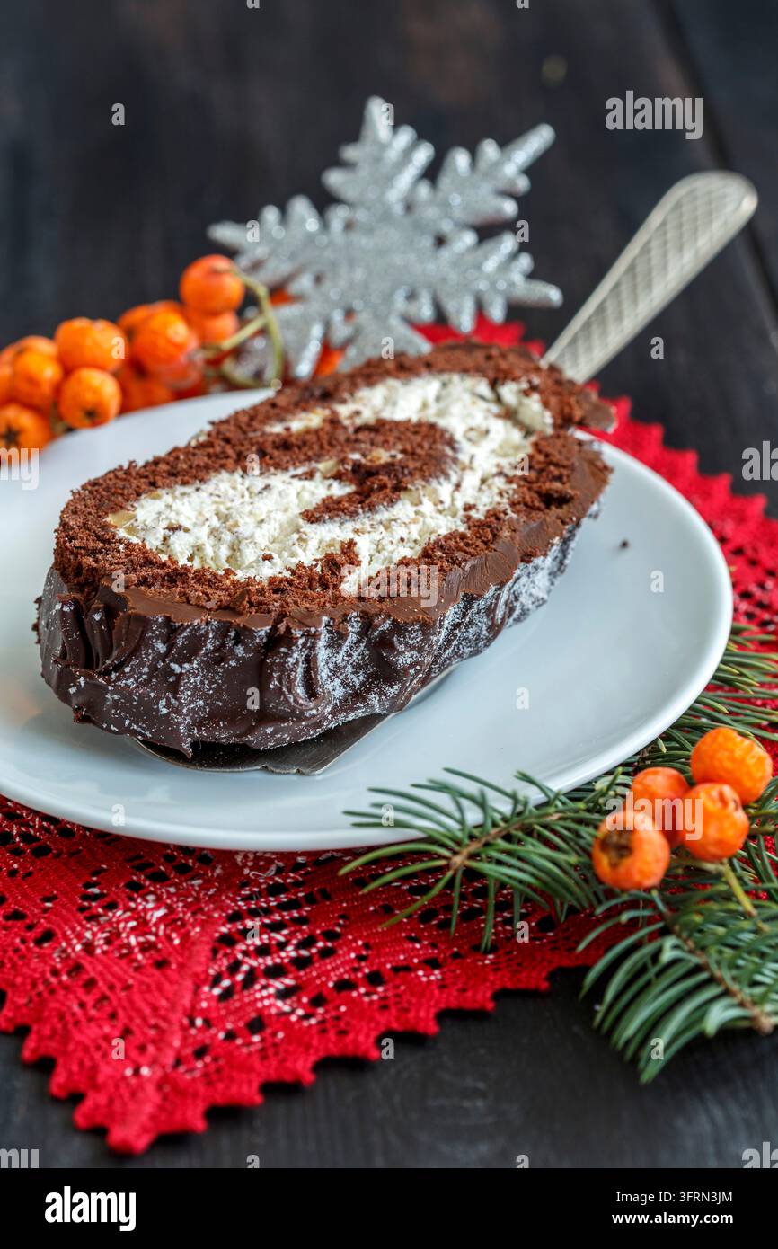 Geschnittene hausgemachte Weihnachts-Schokoladen-Rolle auf einer schönen Spitzenserviette Stockfoto