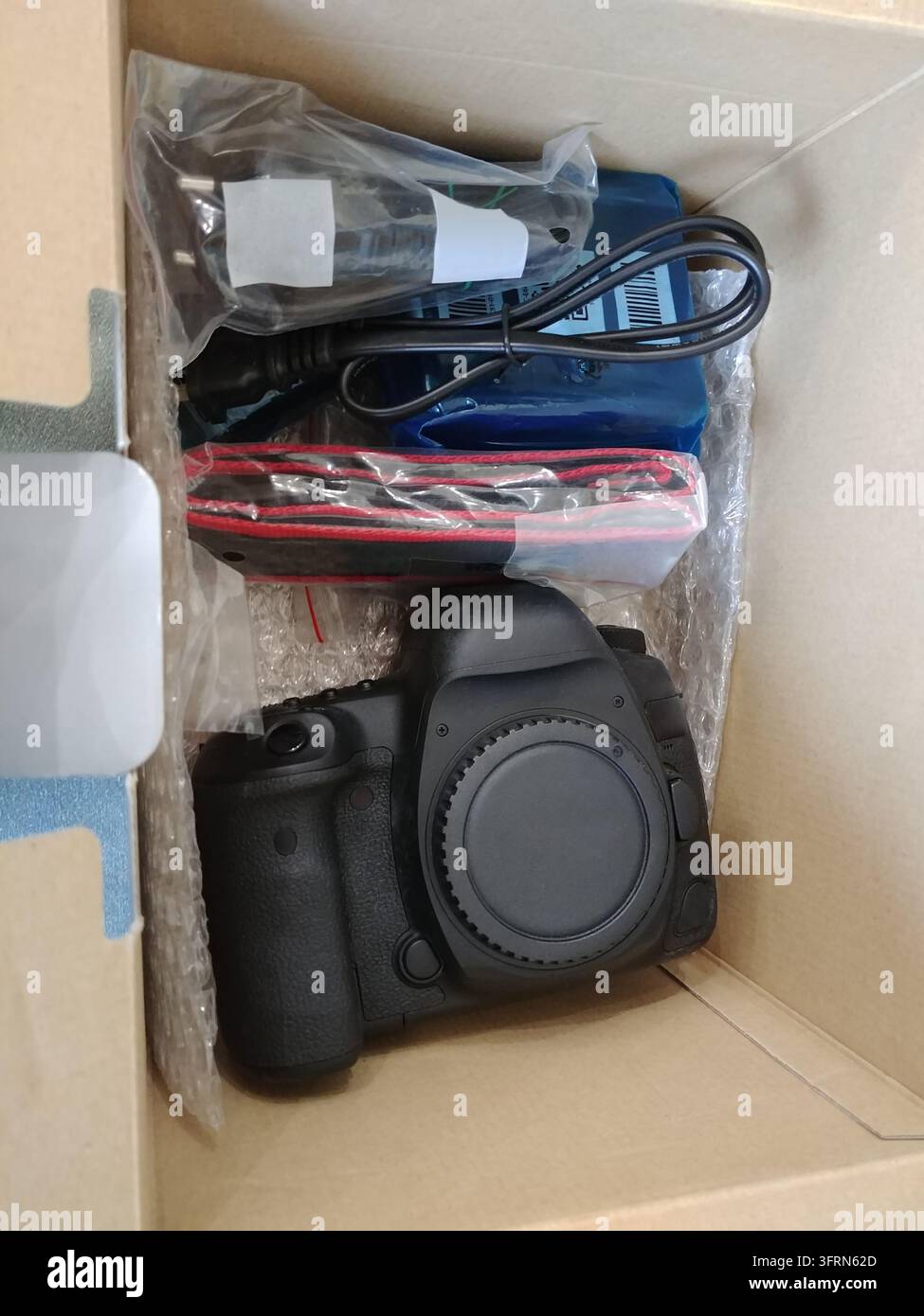 Canon-Kamera mit schwarzem Körper und schwarzem Objektiv. Die neue Kamera befindet sich in einer Box. Die Box ist weiß Stockfoto