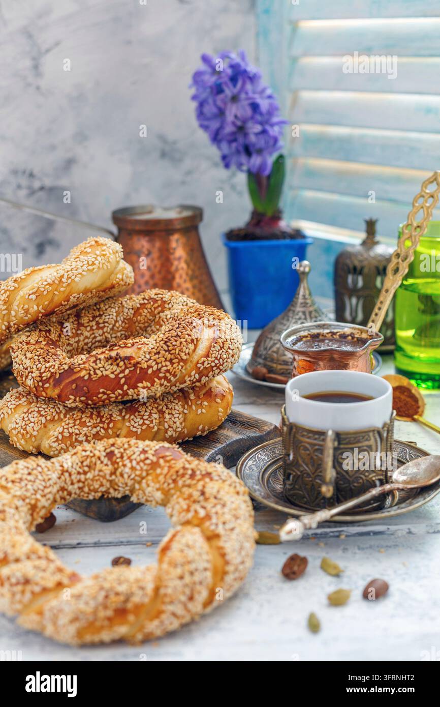 Schwarzer Kaffee und türkische Baguettes mit Sesamsamen auf einem weißen Holztisch Stockfoto