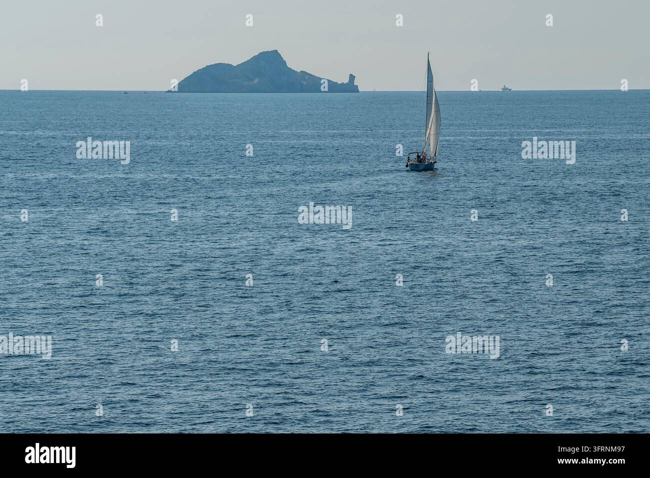 Ein weißes Segelboot segelt mit der Insel Cerboli, in der Provinz Livorno, Italien, im Hintergrund Stockfoto