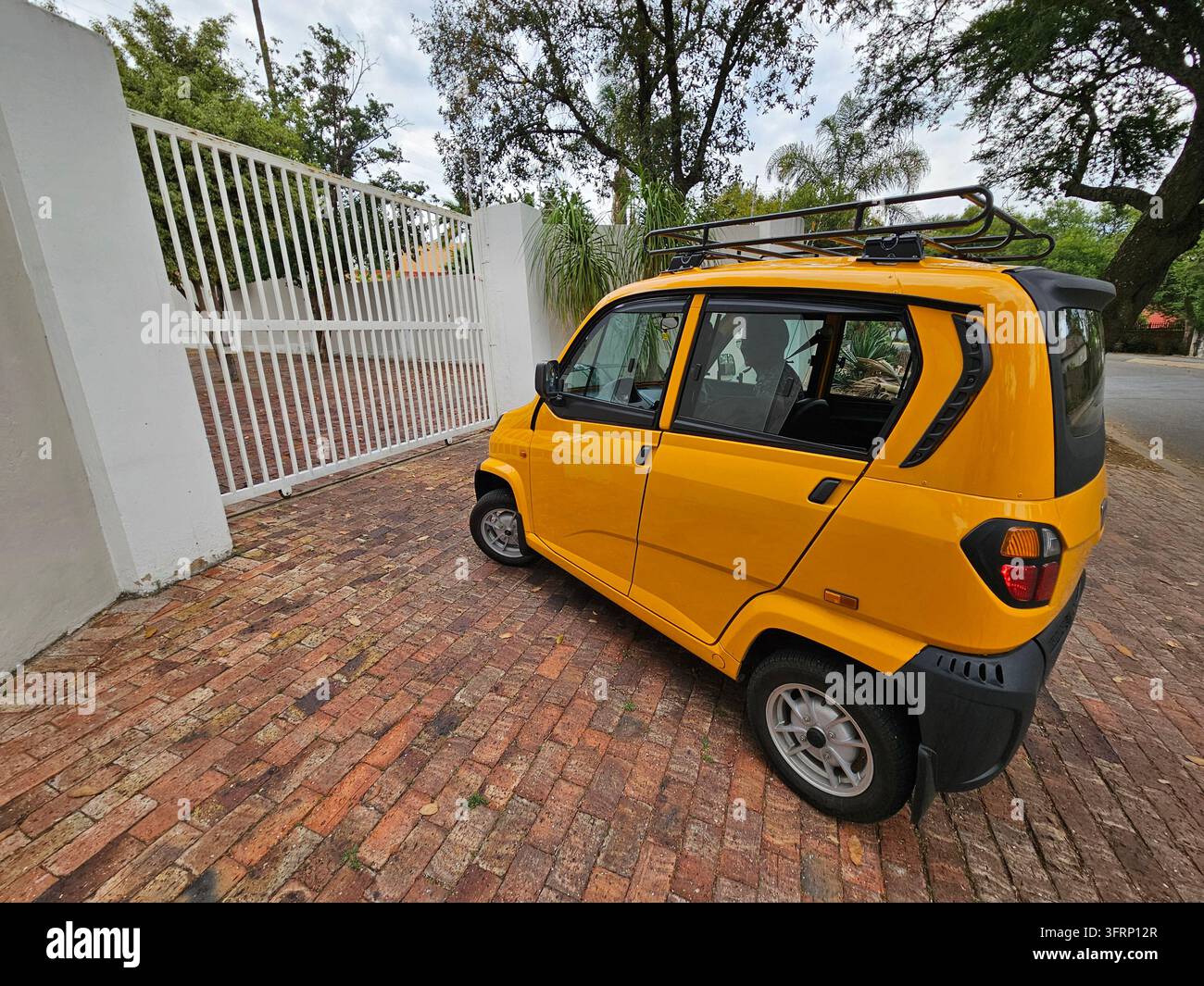 JOHANNESBURG - 28. NOVEMBER 2023: Gelbes Taxi ist vor einem weißen Tor geparkt. Das Auto hat ein Dachgepäckträger oben in Südafrika Stockfoto