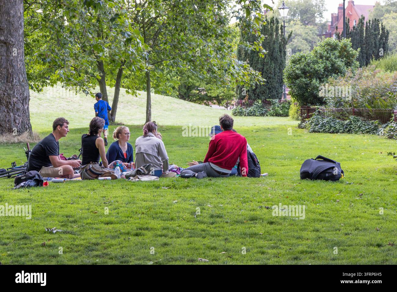 Gruppe von Freunden, die auf dem Gras in einem Park sitzen. London, UK, 29. Juli 2023 Stockfoto