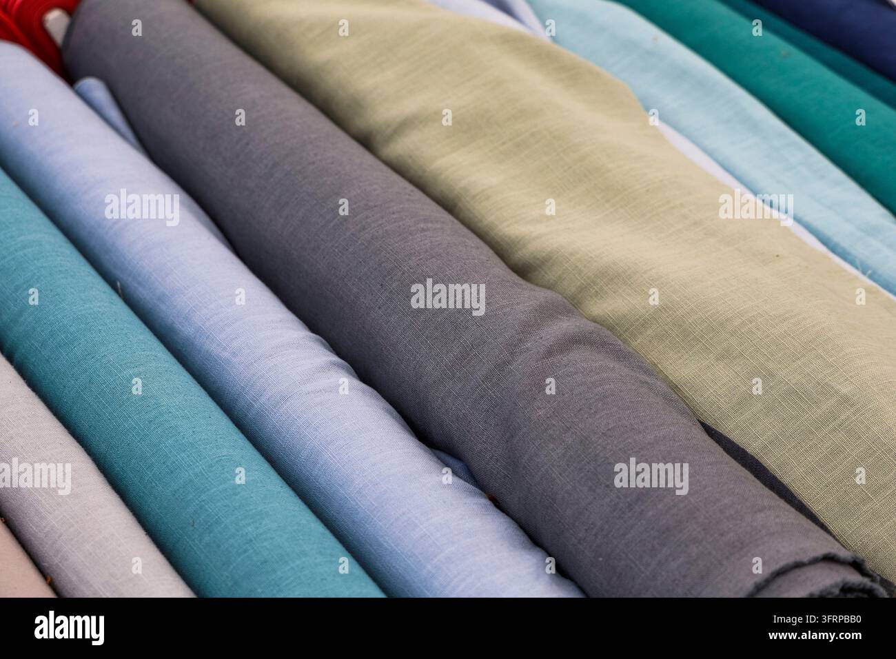 Rollen aus farbigem Leinenstoff in verschiedenen Texturen und Farben, ideal für Mode, Polsterung und Innenarchitekturprojekte Stockfoto