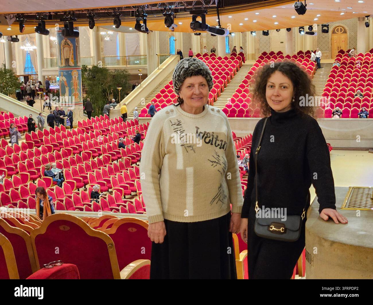 MOSKAU - 25. FEB. 2024: Zwei Frauen stehen in einem roten Theater. Die Ältere von ihnen trägt einen Pullover, auf dem etwas steht. Stockfoto
