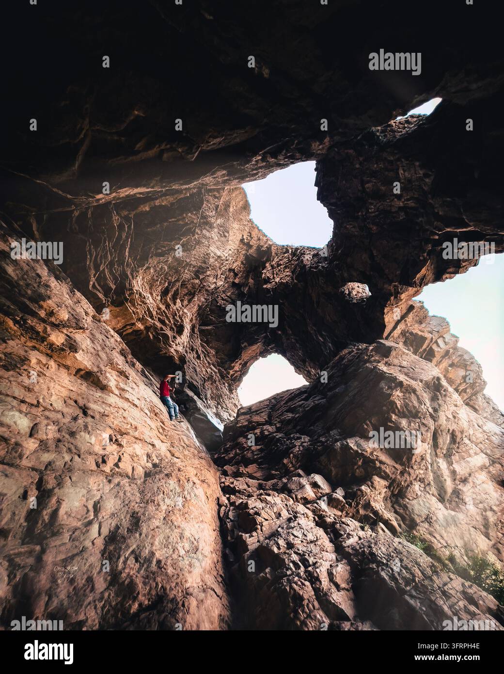 Dramatische Ansicht aus einer tiefen Felshöhle mit Blick auf Steinbögen und eine Öffnung, die den Himmel einrahmt Stockfoto