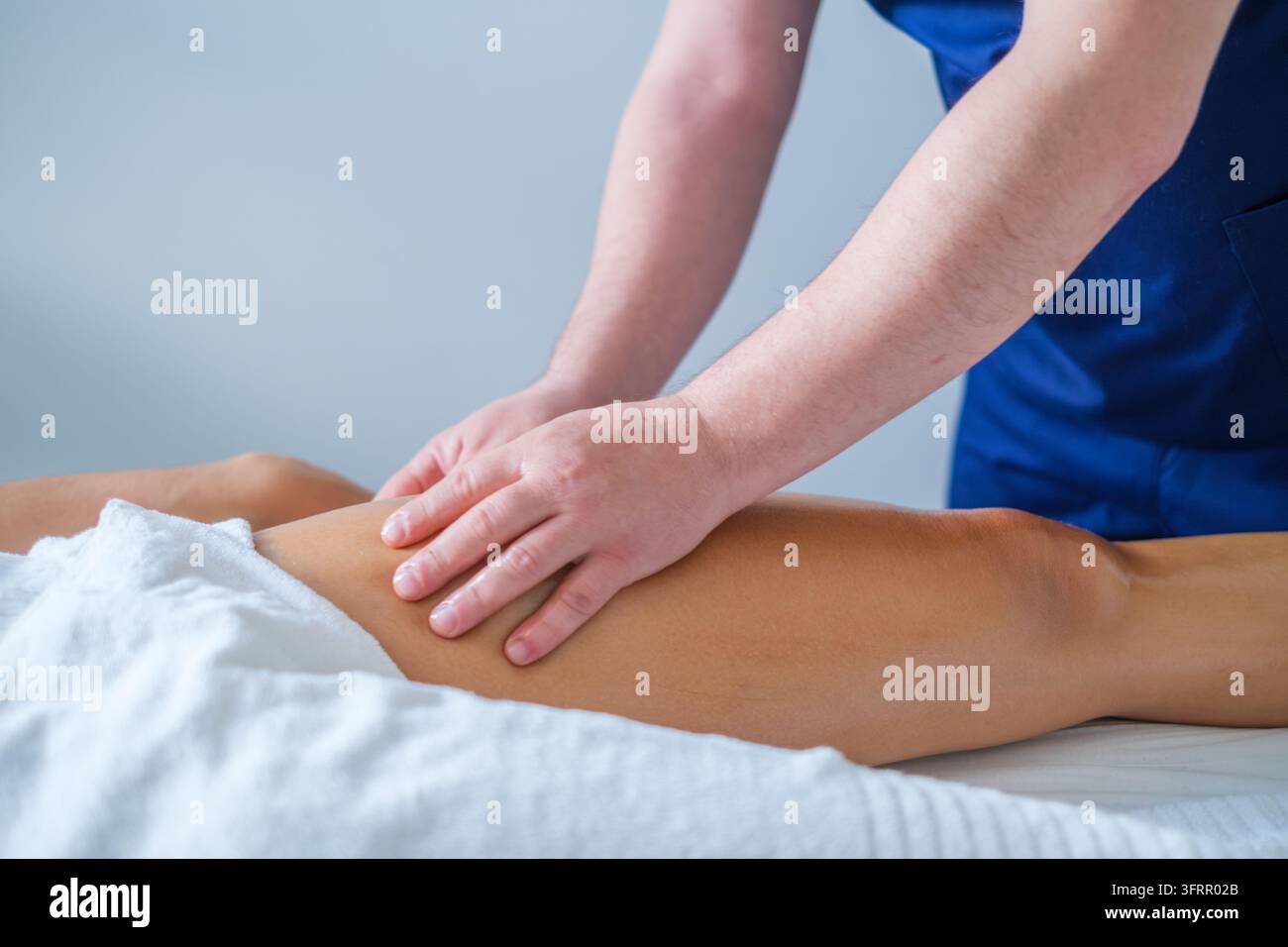 Spa-Center-Szene mit Oberschenkelmassage, einem Massagetherapeuten, Beinmassage, Oberschenkelmassage, therapeutischer Massage und einer Frau Stockfoto