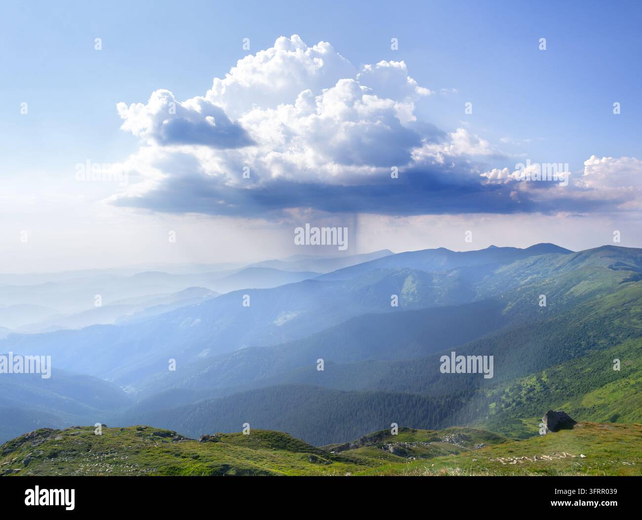 Dramatische Landschaft eines einzelnen Gewitterwolken mit fallendem Regenschleier über Bergketten unter einem klaren blauen Himmel. Hochgebirgs-Panorama Stockfoto