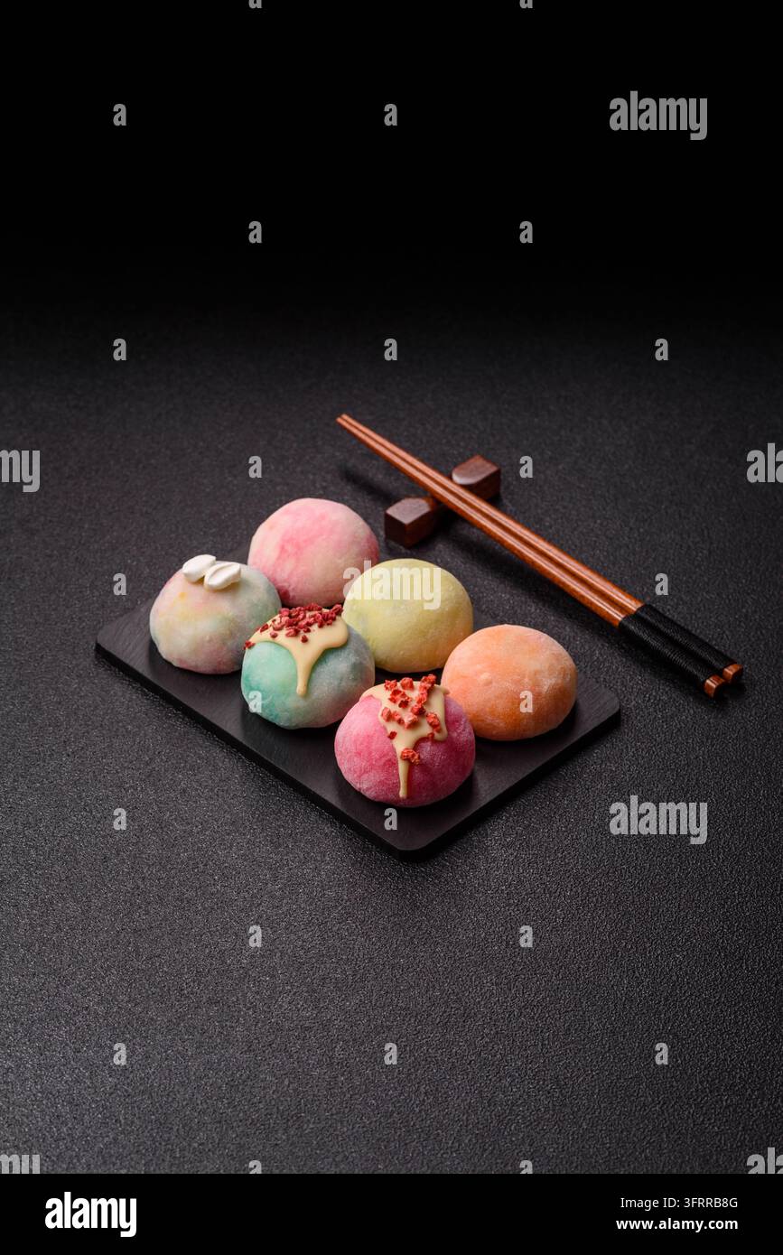 Asiatisches japanisches Mochi-Dessert in verschiedenen Farben und Fruchtgeschmacksrichtungen. Mochi-Dessert als Lebensmittelhintergrund für Ihr Design Stockfoto
