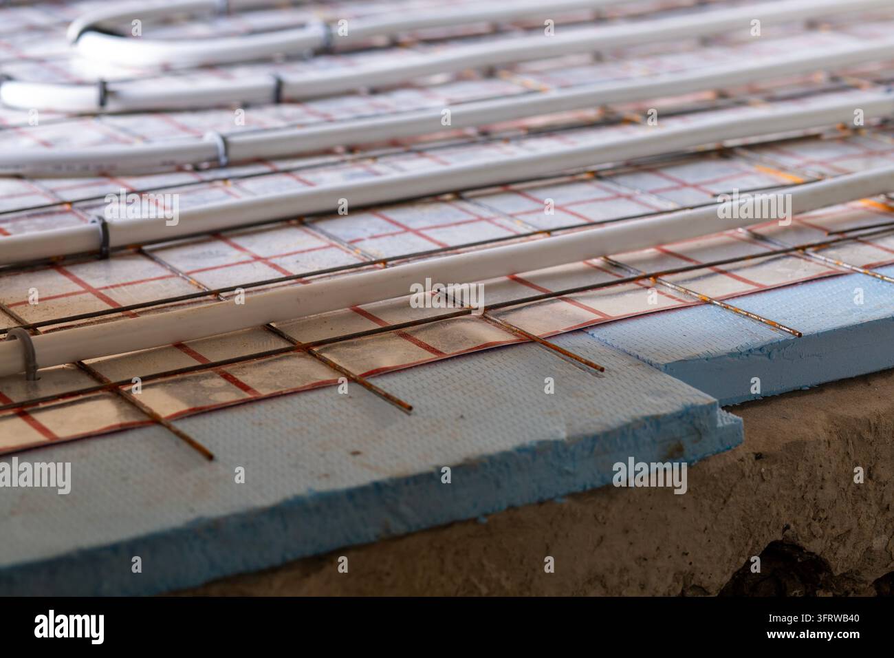 Professionelle Installation von Fußbodenheizungsrohren in einem neuen Zuhause. Isolierte Rohre, moderne Bauweisen und effiziente Raumklimaregulierung. Stockfoto