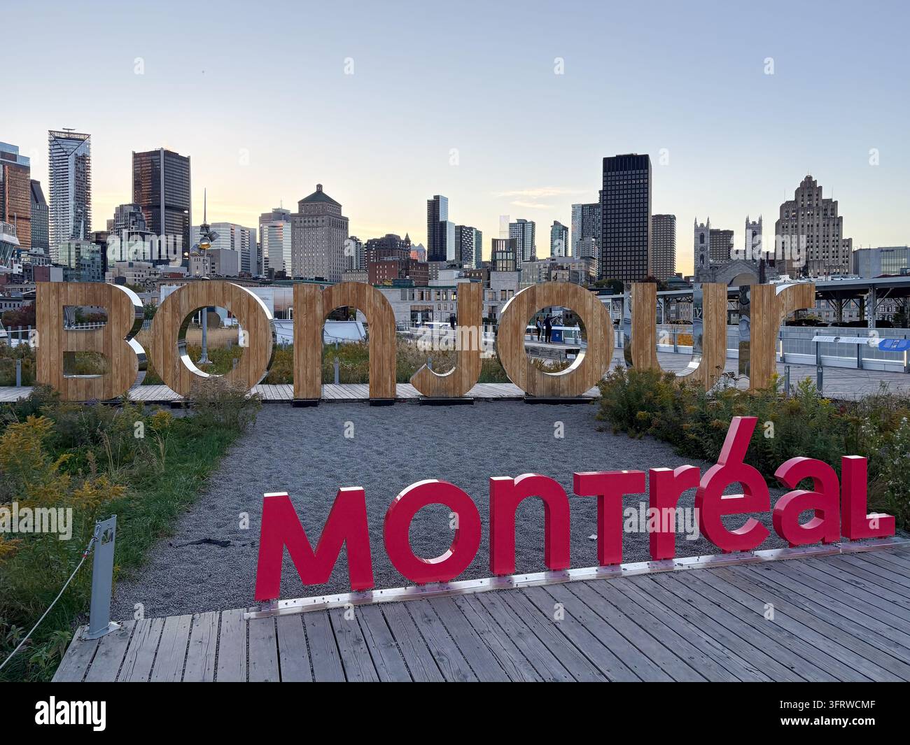 Das Bonjou-Montreal-Schild im alten Hafen von Montreal mit großen hölzernen und roten Buchstaben vor der Kulisse der Stadt Skyline. Stockfoto