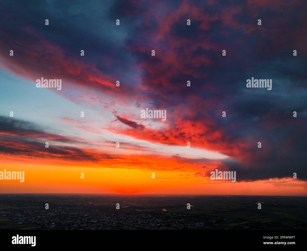 Intensive Sonnenuntergangsfarben malen Abendwolken mit feurigen roten und tiefblauen Tönen Stockfoto