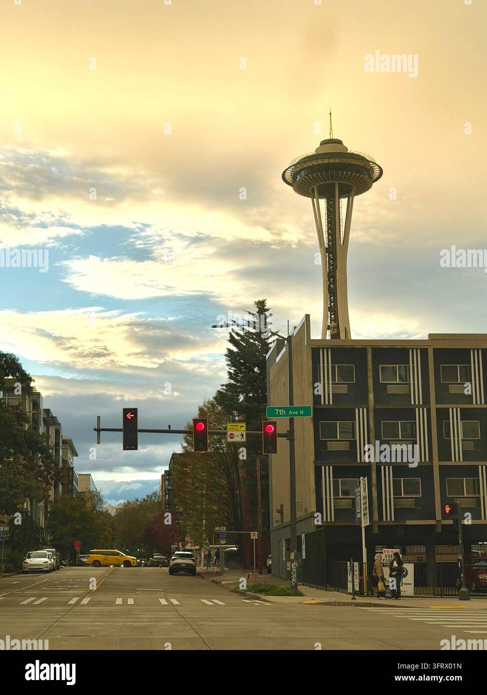 Der Space Needle erhebt sich über einer Straße in Seattle unter einem dramatischen goldenen Abendhimmel. Stockfoto