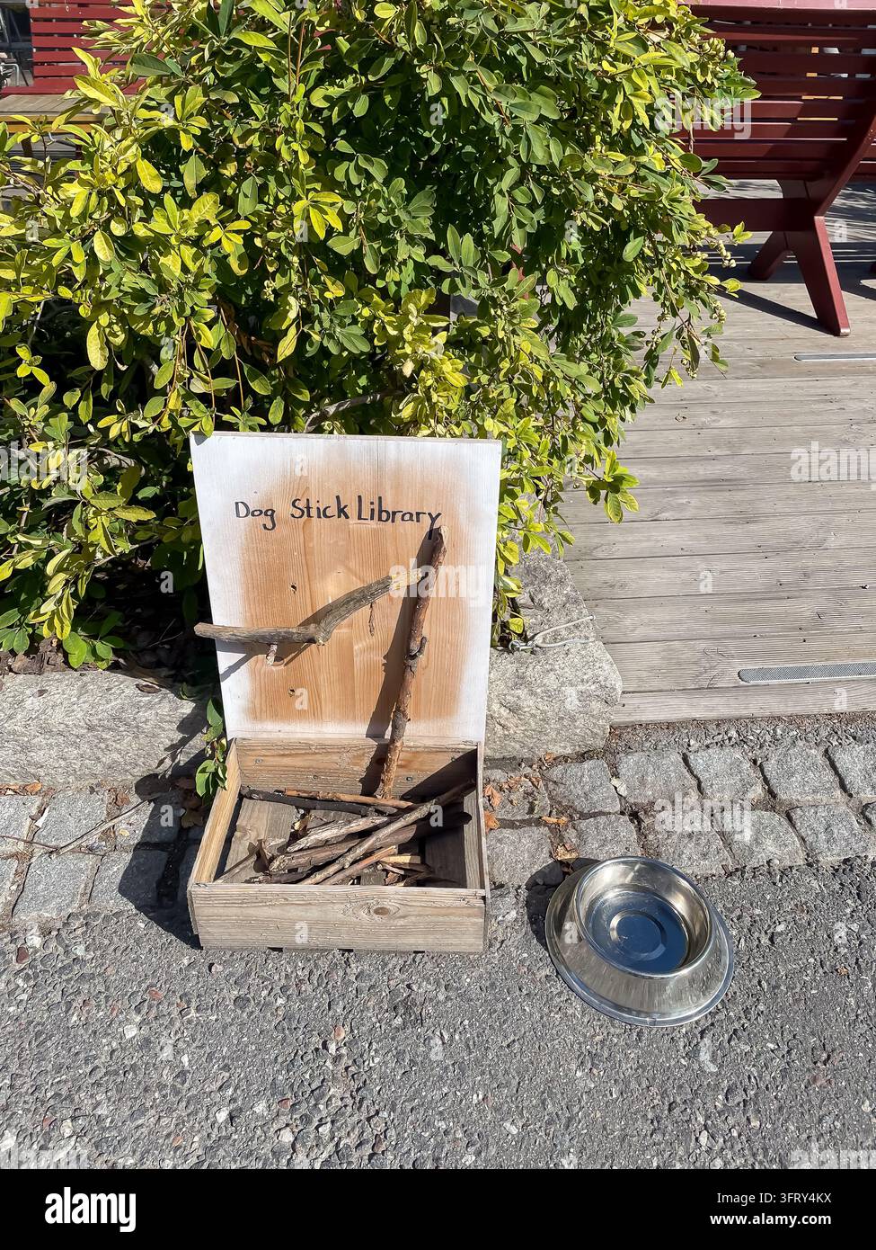 Holzkiste mit Stöcken für Hunde, die auf der Straße als Hunde-Stöcken-Bibliothek dient, skurrile Stadt- und Haustier-Szene Stockfoto