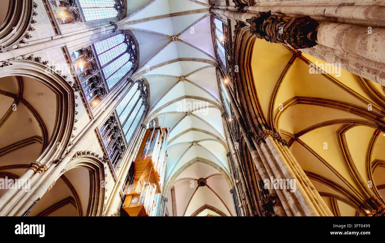 KÖLN, DEUTSCHLAND 4. SEPTEMBER 2026: Ein farbenfrohes Bleiglasfenster unter Rippengewölben im Kölner Dom. Stockfoto