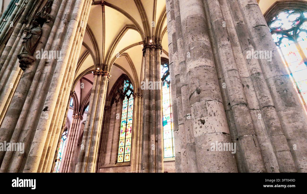 KÖLN, DEUTSCHLAND 4. SEPTEMBER 2026: Ein farbenfrohes Bleiglasfenster unter Rippengewölben im Kölner Dom. Stockfoto