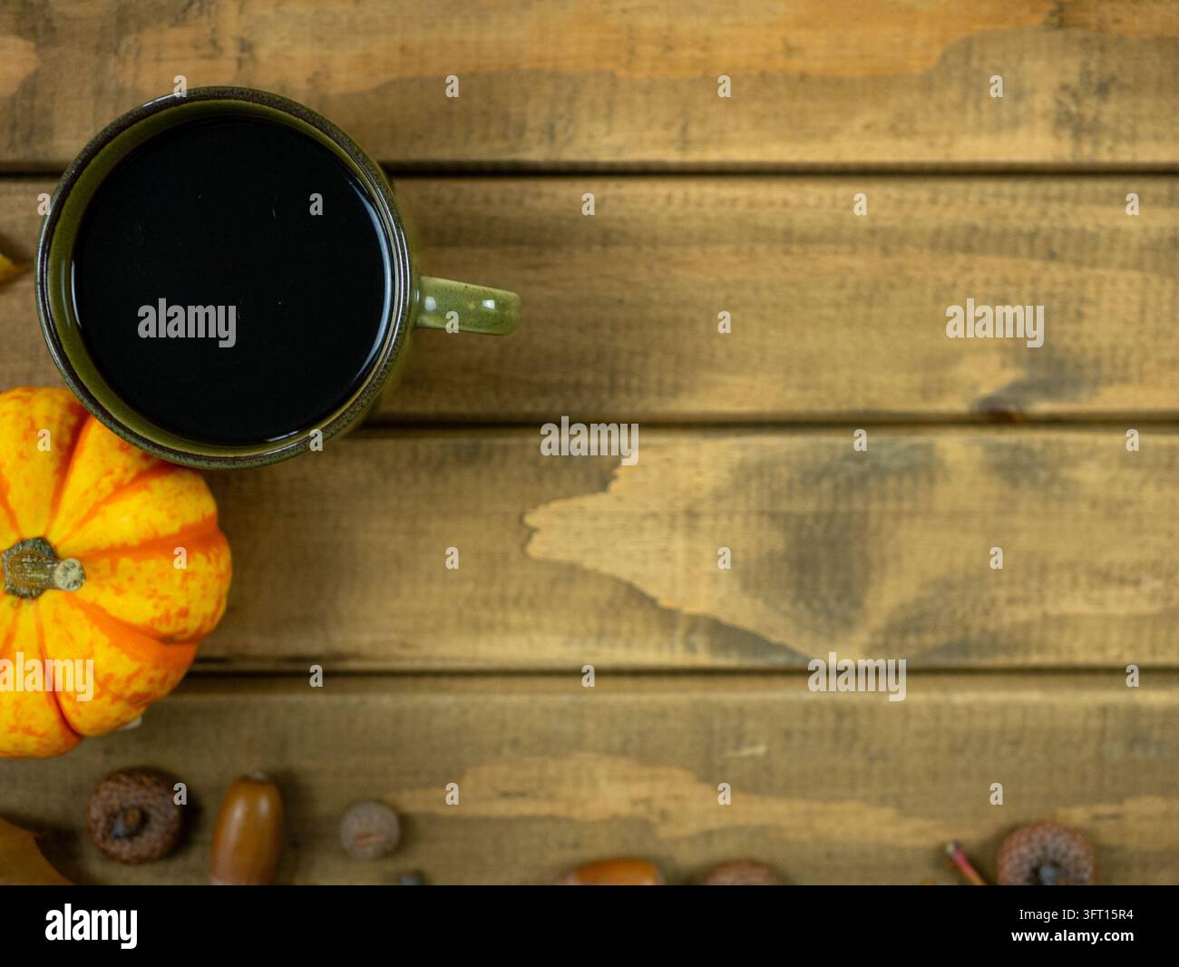 Minimale Herbst-Kaffeeszene mit dunkler Tasse und orangefarbenem Kürbis auf hellem Holztisch, Oktober-Getränkehintergrund mit Kopierraum Stockfoto