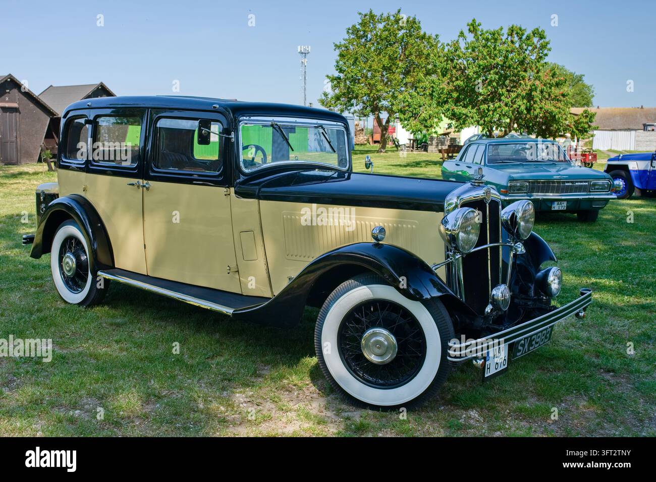 Englische Beschreibung (Description): Eine Automobilfotografie, die ein historisches Oldtimer-Auto mit einem zweifarbenen gelb-schwarzen Karosseriedesign und weißer Wandverkleidung zeigt Stockfoto