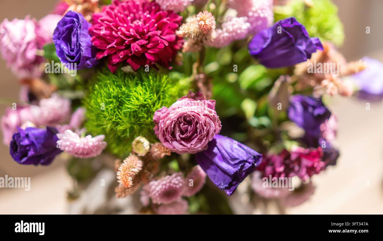 Farbenfrohes Blumenbouquet mit violettem Lisianthus, einer rosa Rose, magentafarbenem Chrysantheme und grünen Dianthus-Kugeln, von oben aufgenommen mit einem weichen unscharfen Hintergrund Stockfoto
