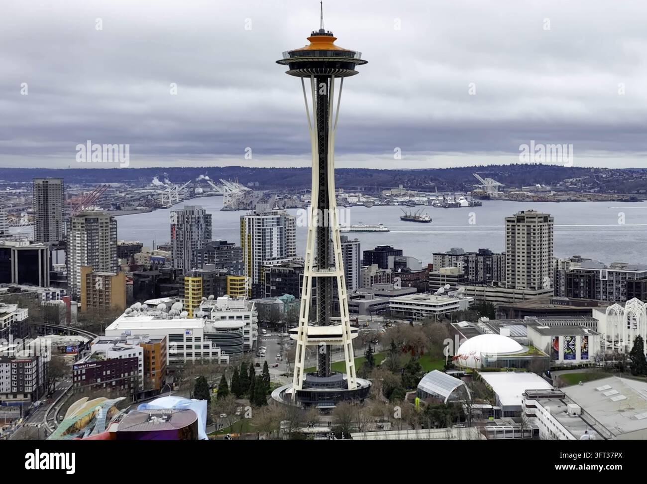 Luftbild des Space Needle, der über der Skyline von Seattle aufragt, mit städtischen Gebäuden, Elliott Bay und einem bewölkten Himmel im Hintergrund Seattle, WA, U Stockfoto