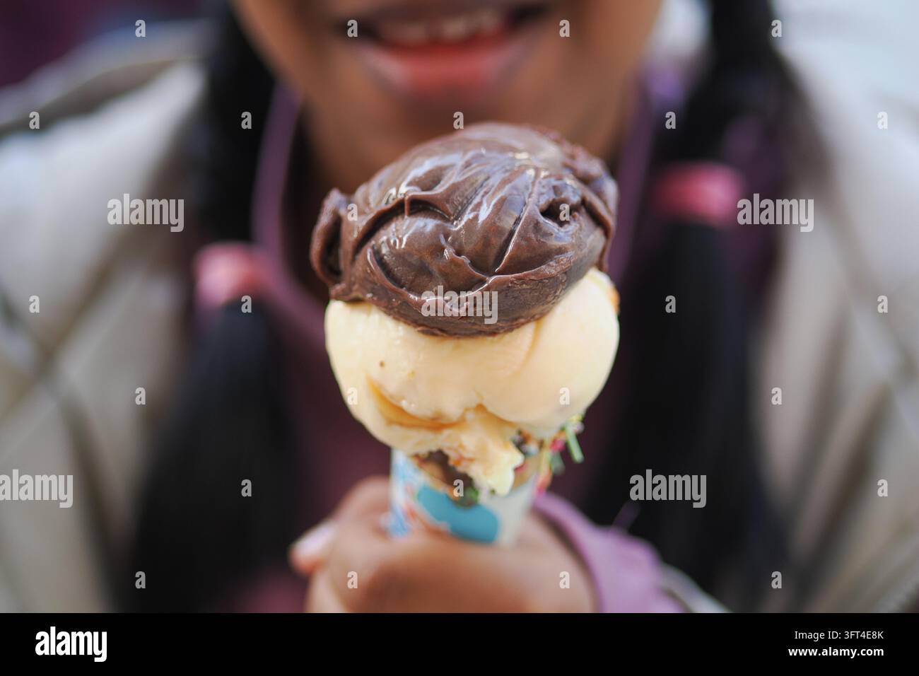 Kind hält eine Eiswaffel mit Schokoladen- und Vanillegeschmack im Park Stockfoto