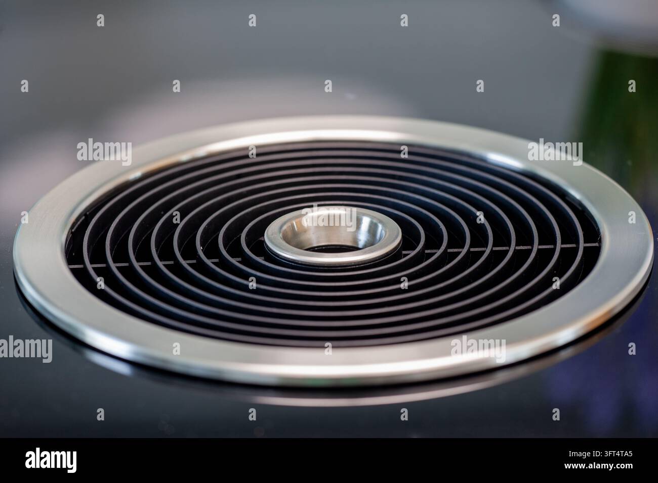 Modernes Dunstabzugssystem, das nahtlos in eine schwarze Induktionskochplatte integriert ist und effiziente Küchenbelüftung sowie ein schlankes, minimalistisches Design bietet Stockfoto