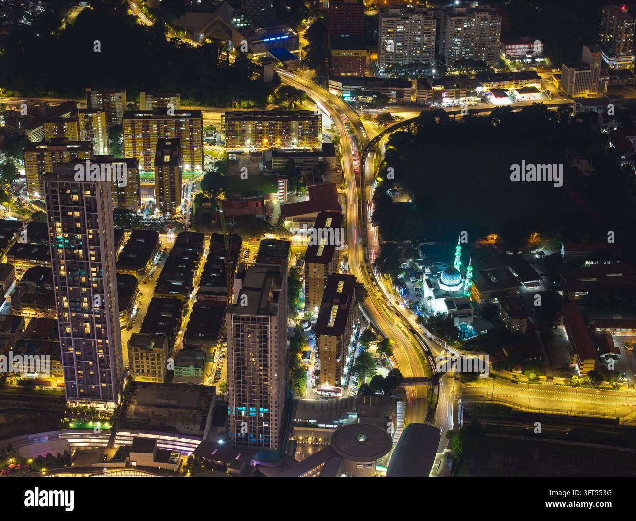 Stadtlichter leuchten unter dem Nachthimmel. Straßen pulsieren mit Bewegung, der Verkehr fließt stetig. Gebäude erheben sich hoch in Kuala Lumpur Stockfoto
