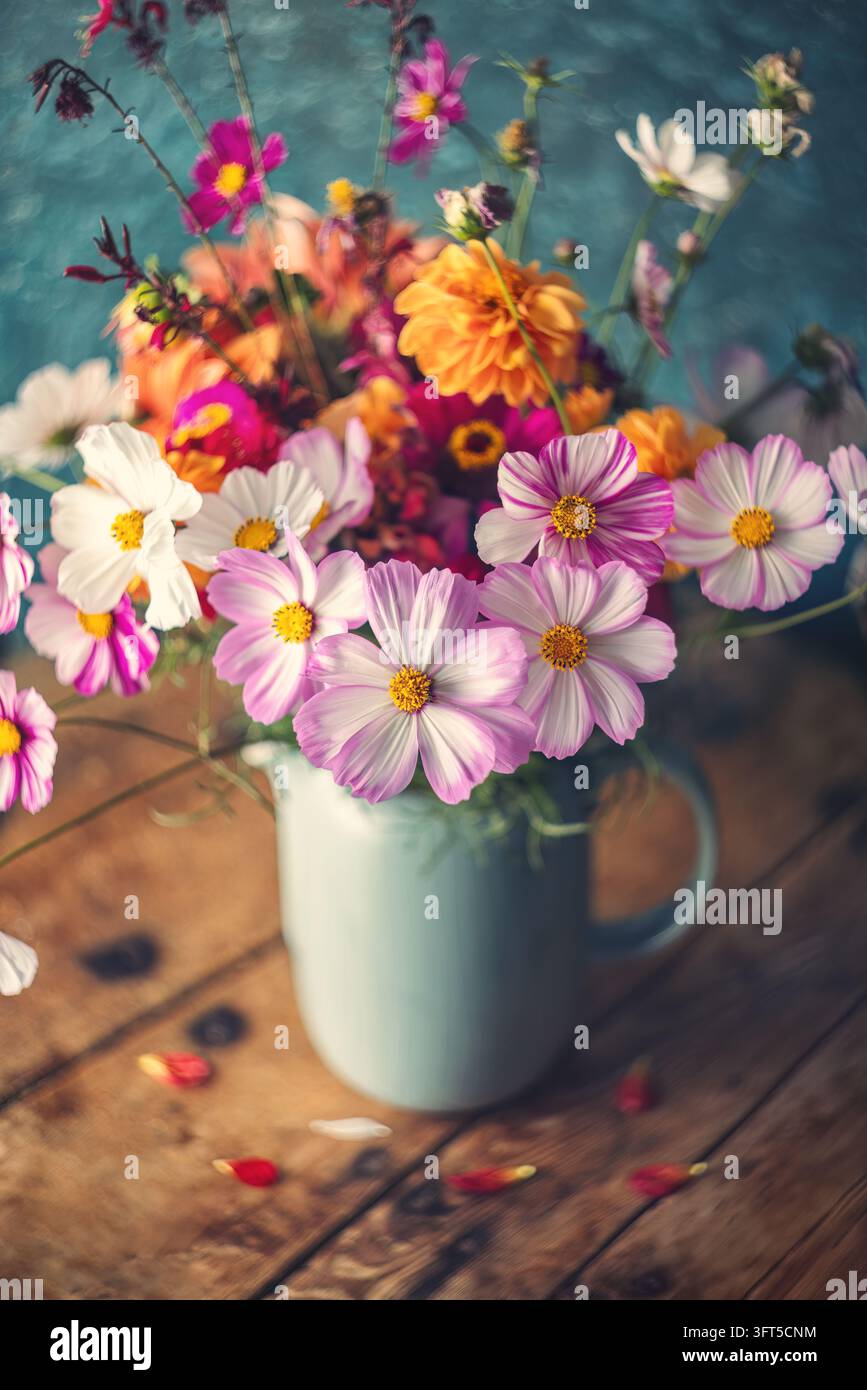Strauß bunter Kosmeien in einem Krug auf einem Holztisch Stockfoto