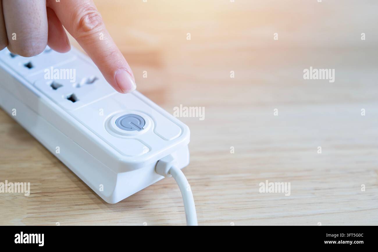 Hand schaltet eine Steckdose zum Energiesparen aus. Energiesparkonzept Stockfoto