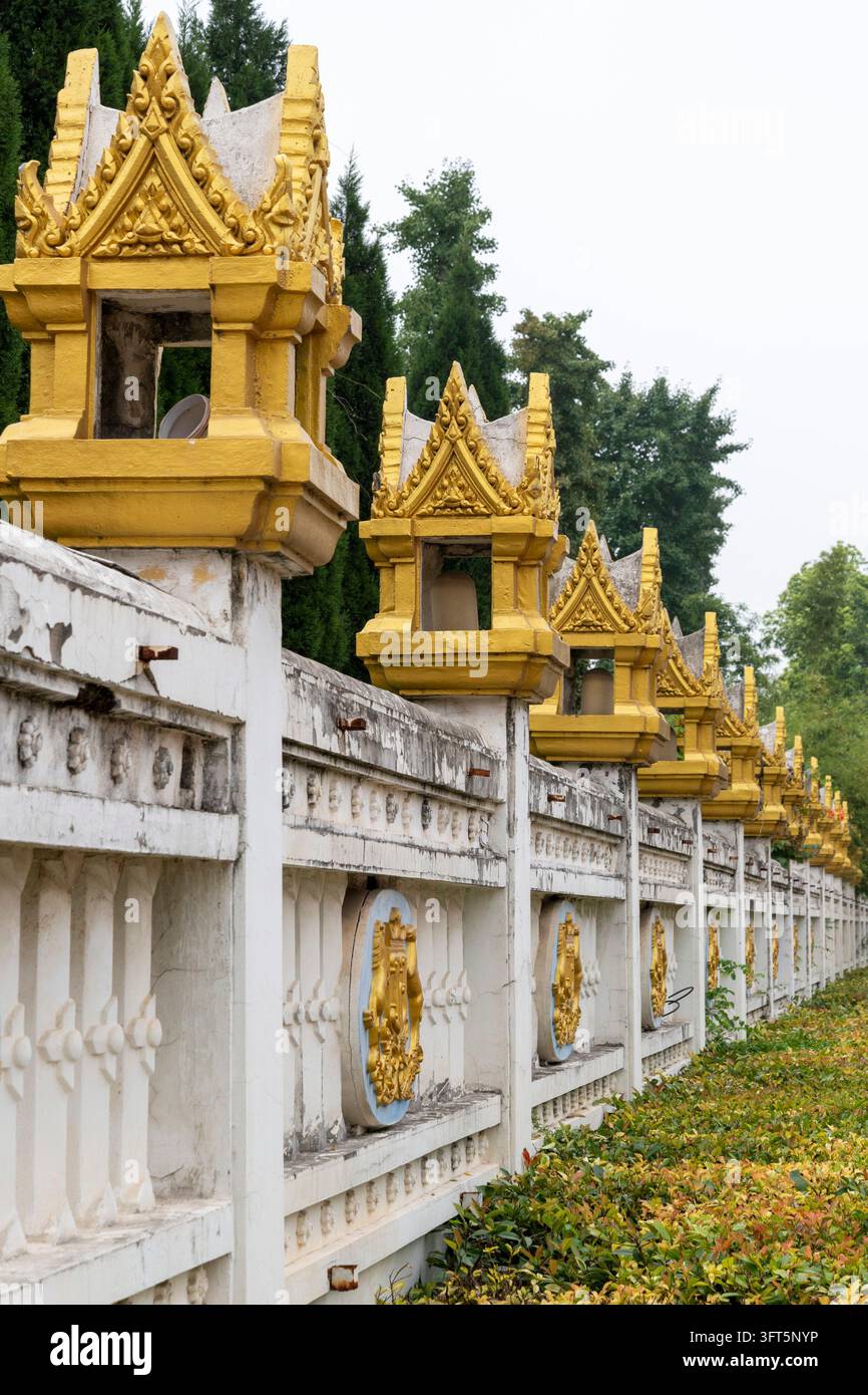Eine Tempelgrenzmauer, die mit kleinen vergoldeten schreinartigen Ornamenten und verzierten Paneelen gekrönt ist, in Luoyang, Henan, China. Stockfoto