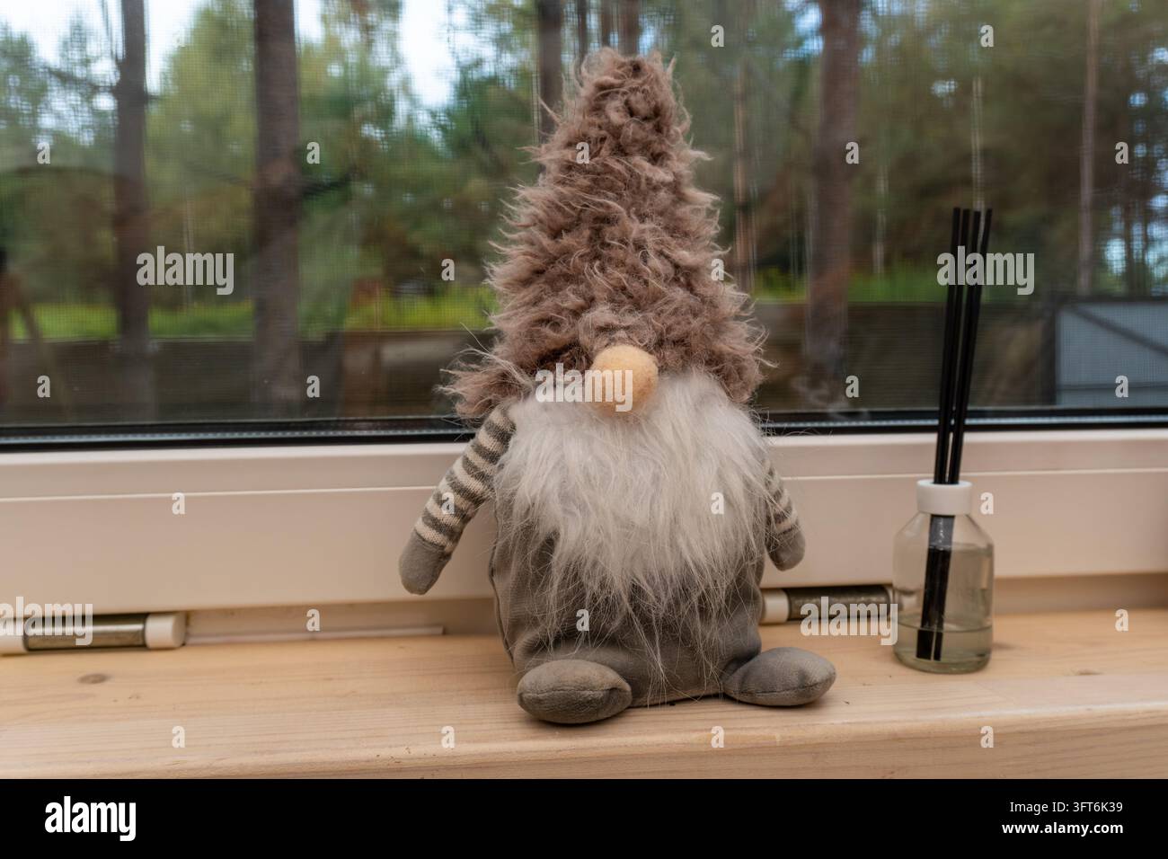 Dekorativer Spielzeuggnom und Schilf-Diffusor auf der Fensterbank Stockfoto