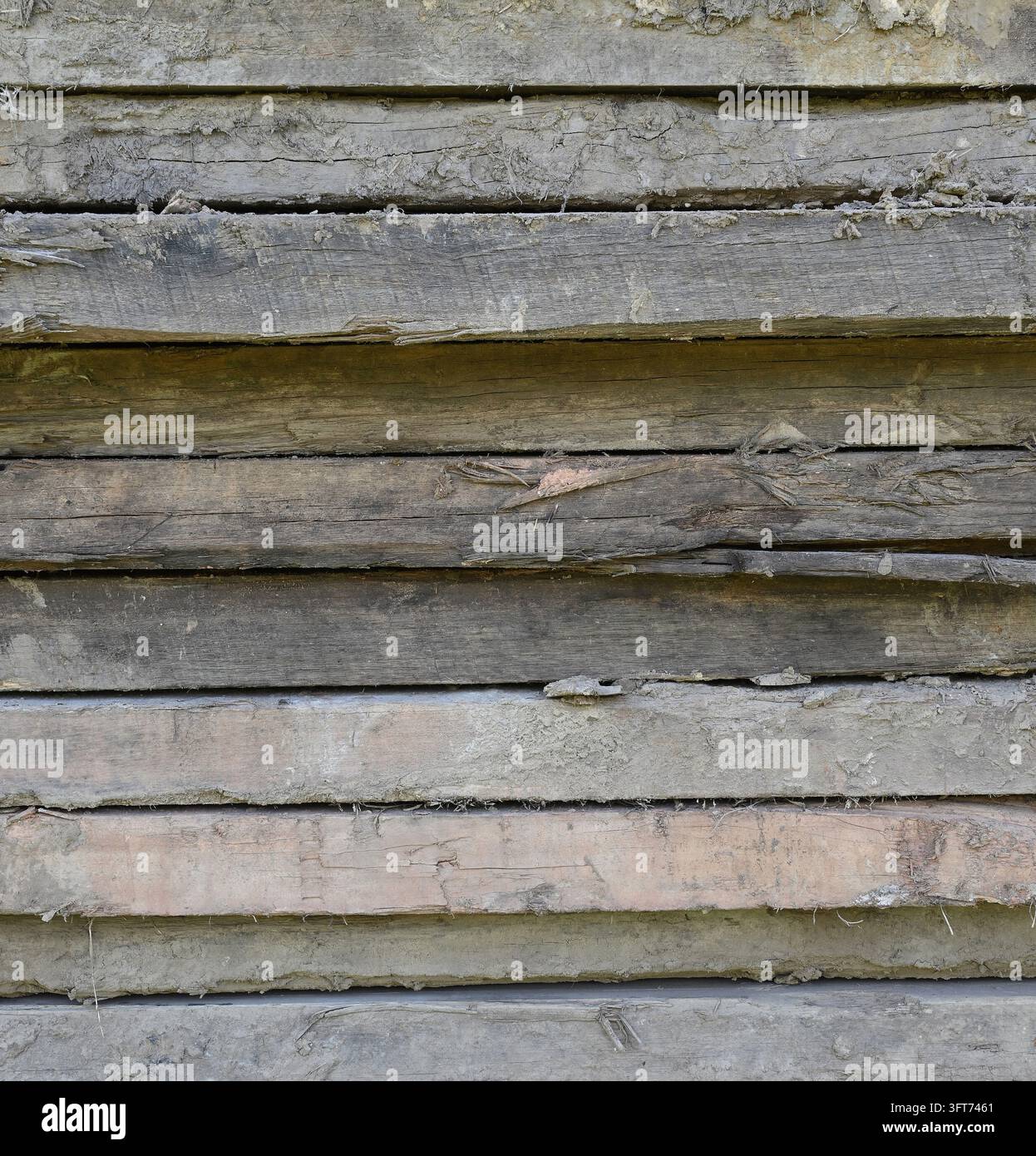 Nahaufnahme von schlammigem gestapeltem Holz mit ungleichmäßigen hervorstehenden und zurückspringenden Bretterseiten, Holzmaserung, Splittern, Beulen, Rissen, Splittern, einem gespaltenen Brett Stockfoto