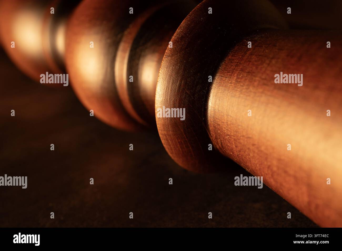 Detaillierte Makroaufnahme eines polierten gedrehten Holzmöbelbeins mit abgerundeten dekorativen Formen und sichtbarer Holzmaserung. Warme Beleuchtung, rustikale Atmosphäre. Stockfoto