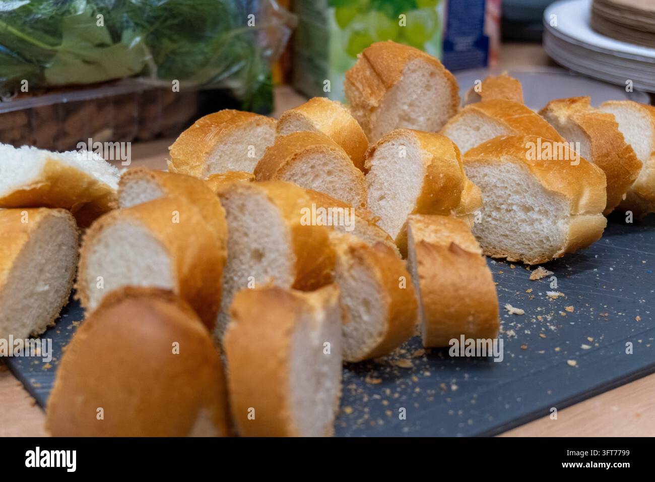 Geschnittenes frisches französisches Baguette-Brot auf schwarzer Schieferplatte Stockfoto
