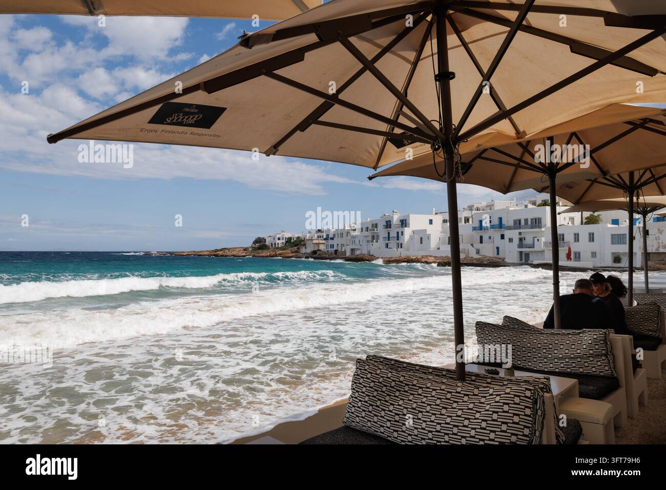 Wellen der Ägäu, die am Ufer brechen, gesehen vom Fotis Cafe and Bar in Naousa, Paros, Griechenland. Stockfoto