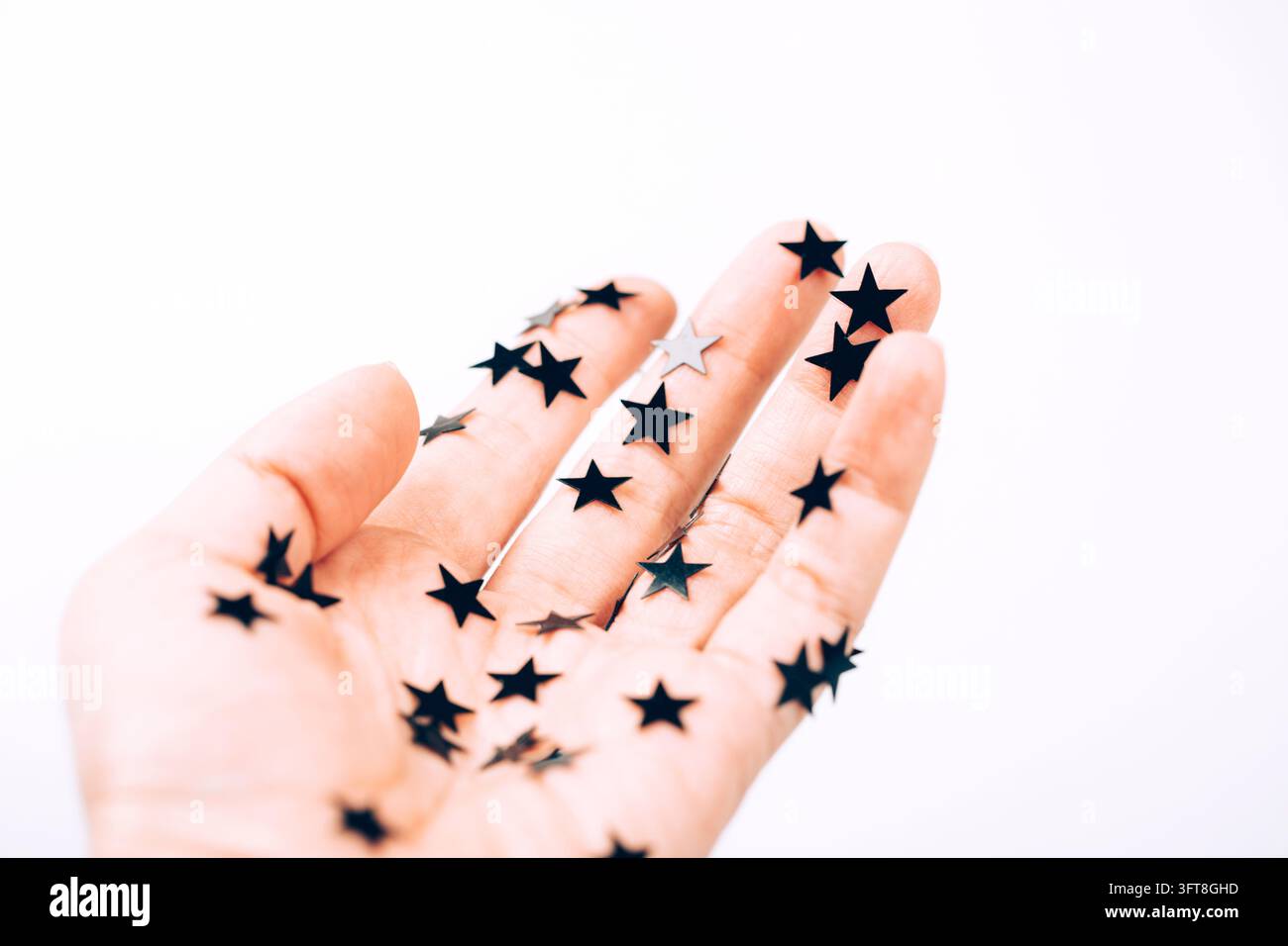 Sternkonfetti, das auf einer offenen Hand verstreut ist, hell Stockfoto