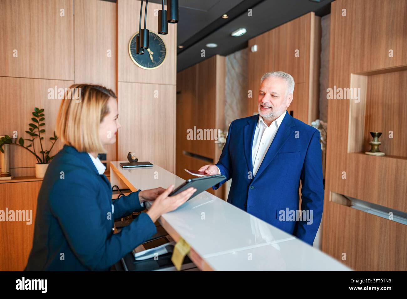Geschäftsmann, der sich an der Hotelrezeption anmeldet Stockfoto