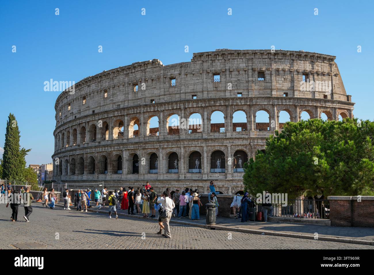 Rom, Italien – 1. Oktober 2026: Touristen versammeln sich in der Nähe des antiken Kolosseums in Rom, Italien, mit seinen ikonischen römischen Bögen und der Kopfsteinpflasterstraße Stockfoto