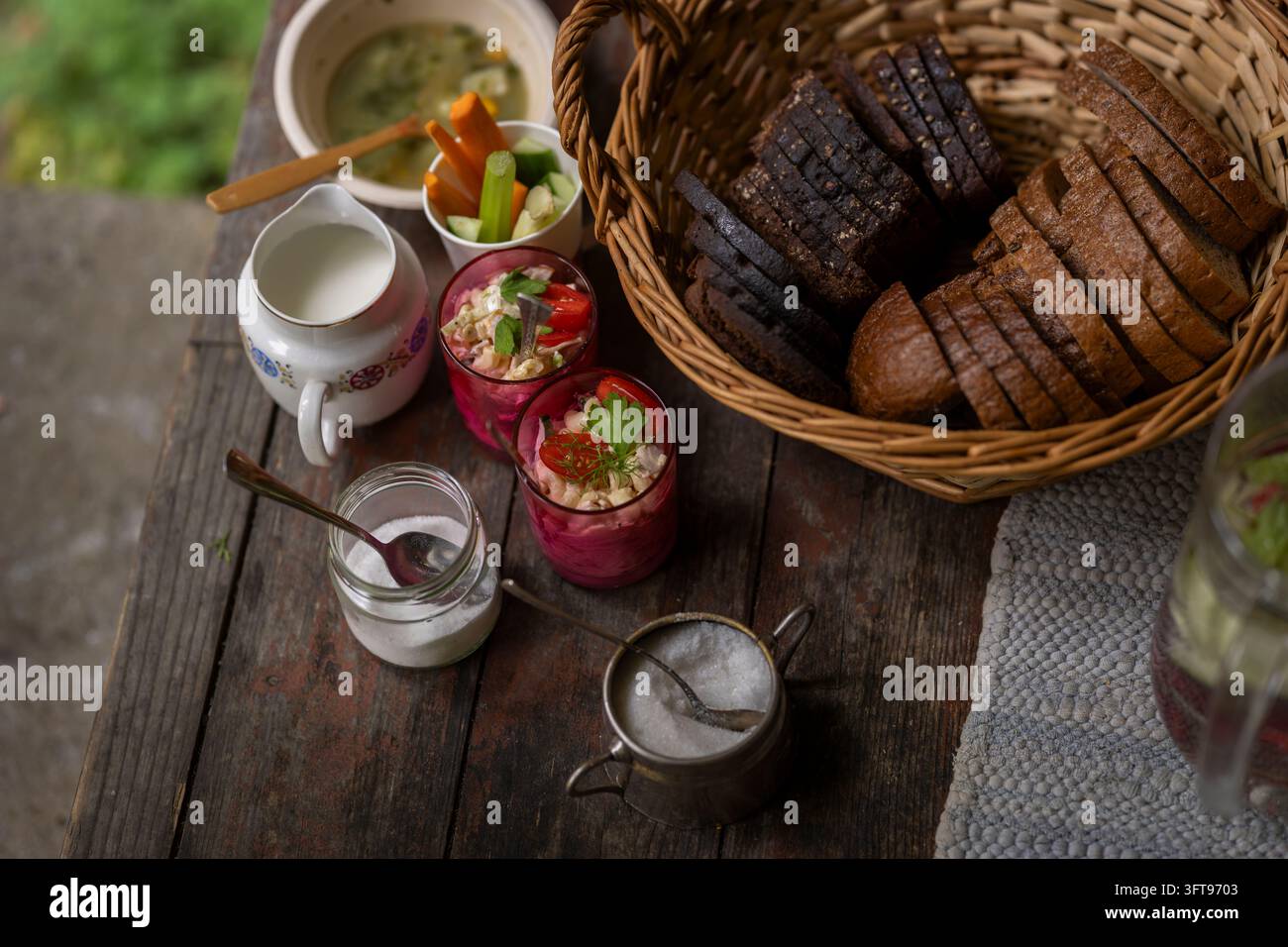 Traditioneller Kartoffelsalat und dunkles Roggenbrot, serviert auf einem rustikalen Holztisch, begleitet von cremiger Salatsauce und frischen Gemüsesticks Stockfoto