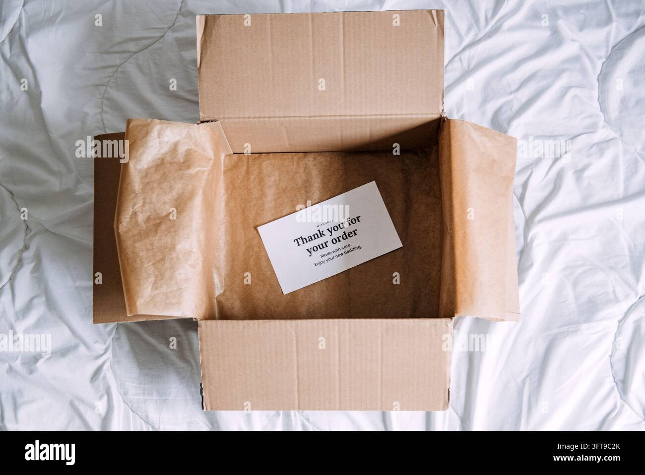 Oberansicht eines geleerten Pakets, das mit Kraftpapier ausgekleidet ist und einen gedruckten Dankesbeleg enthält, fertige Vorlage für Verpackungen und Kundenservice-Visuals Stockfoto