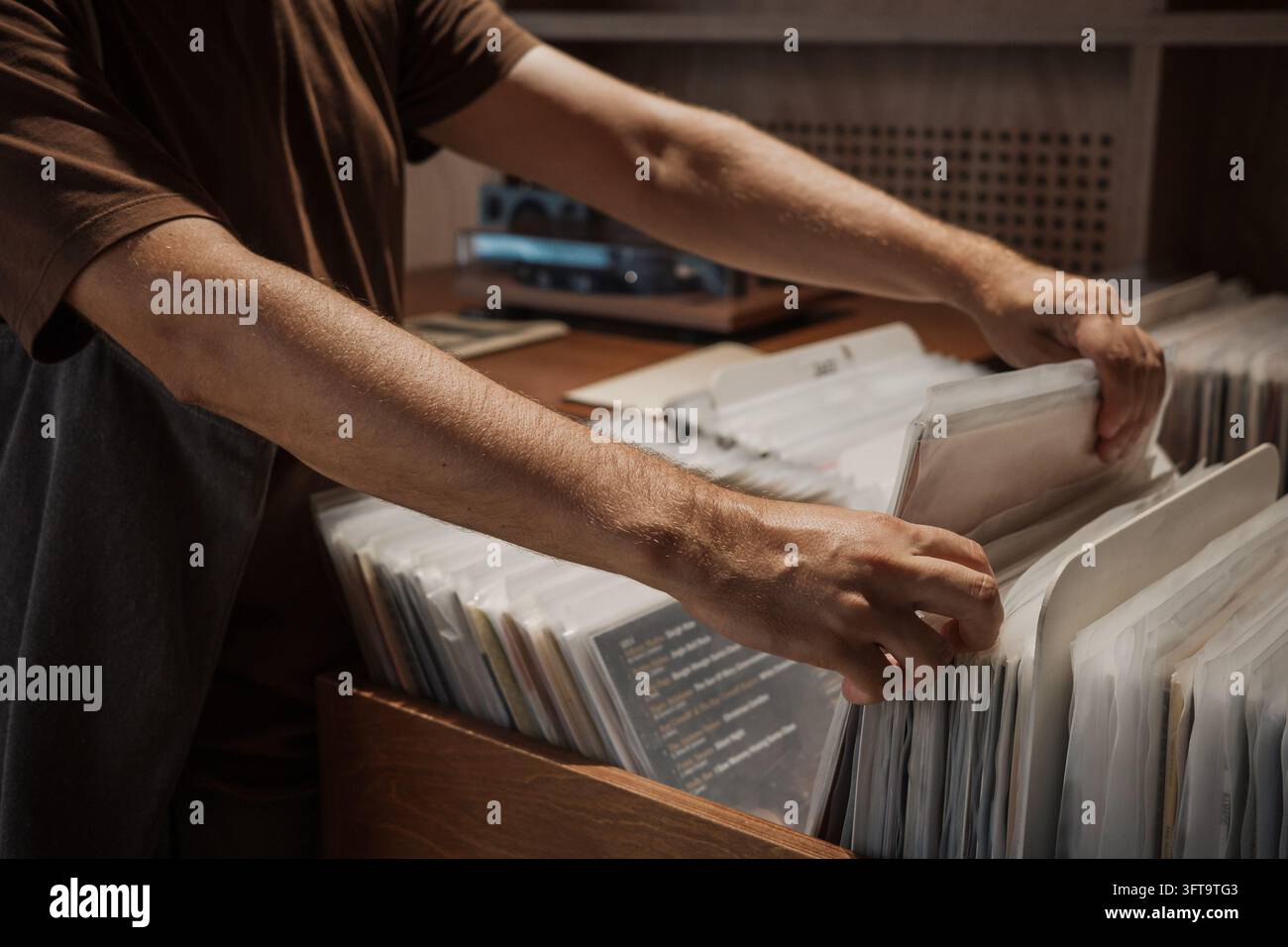Hände blättern durch Vinylplatten in einem Musikgeschäft, Mann durchstöbert Albumhüllen und sucht nach LP-Musik, analoge Klangsammlung, Retro-Einkaufen und nostalgische Unterhaltung. Stockfoto
