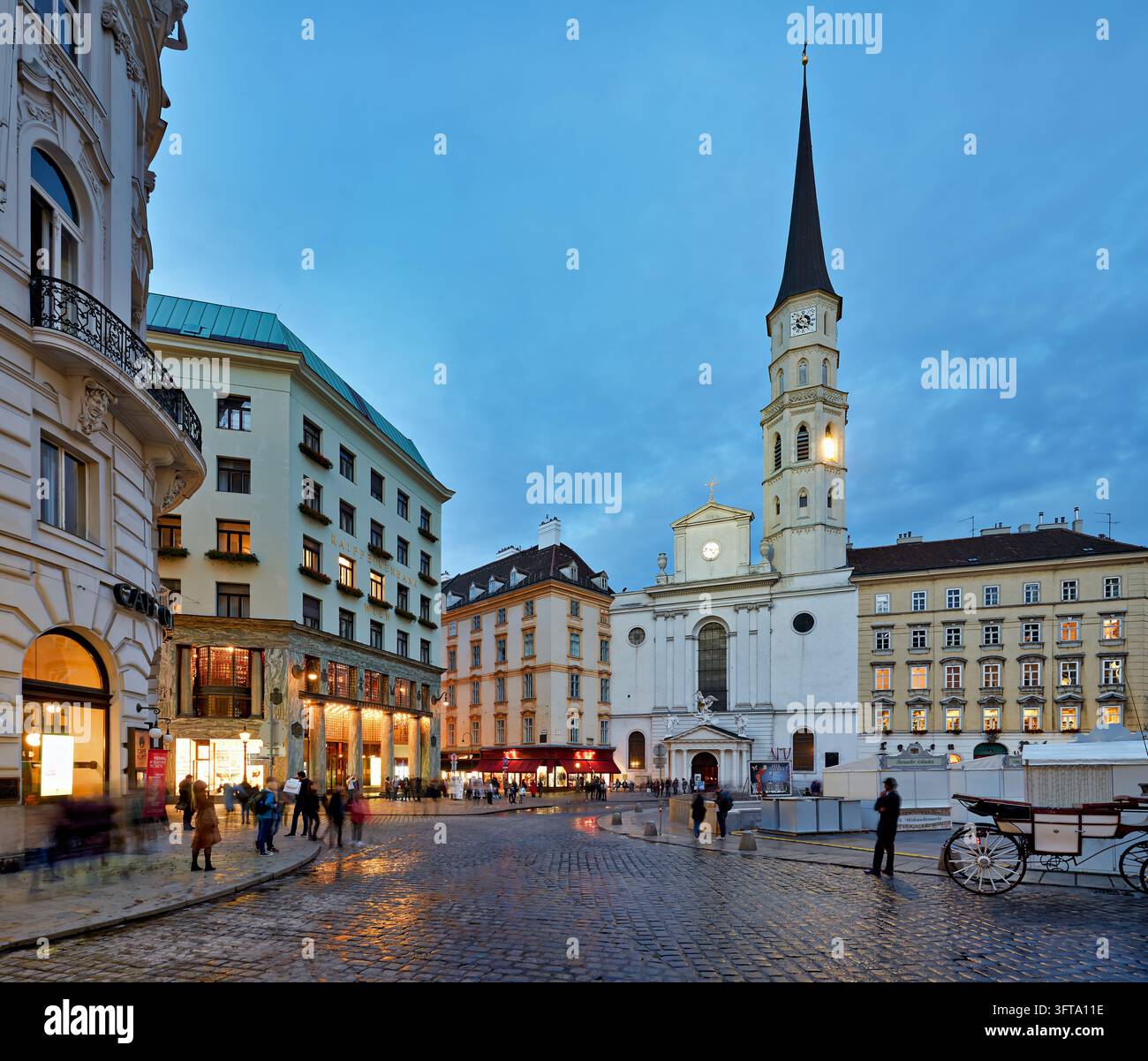 Looshaus von Adolf Loos, eine Fiaker-Kutsche und Fußgänger auf nassen Kopfsteinpflaster in der Blauen Stunde in der Altstadt von Wien, Österreich Stockfoto